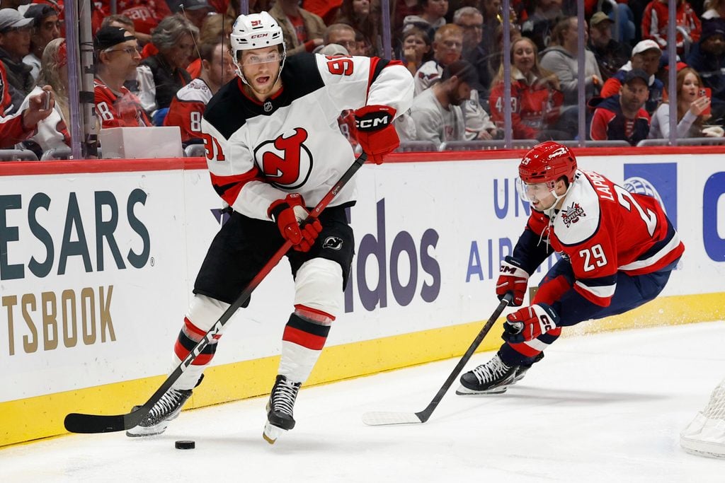Nov 15, 2025; Washington, District of Columbia, USA; New Jersey Devils center Dawson Mercer (91) skates with the puck against as Washington Capitals center Hendrix Lapierre (29) chases during the third period at Capital One Arena. Mandatory Credit: Geoff Burke-Imagn Images