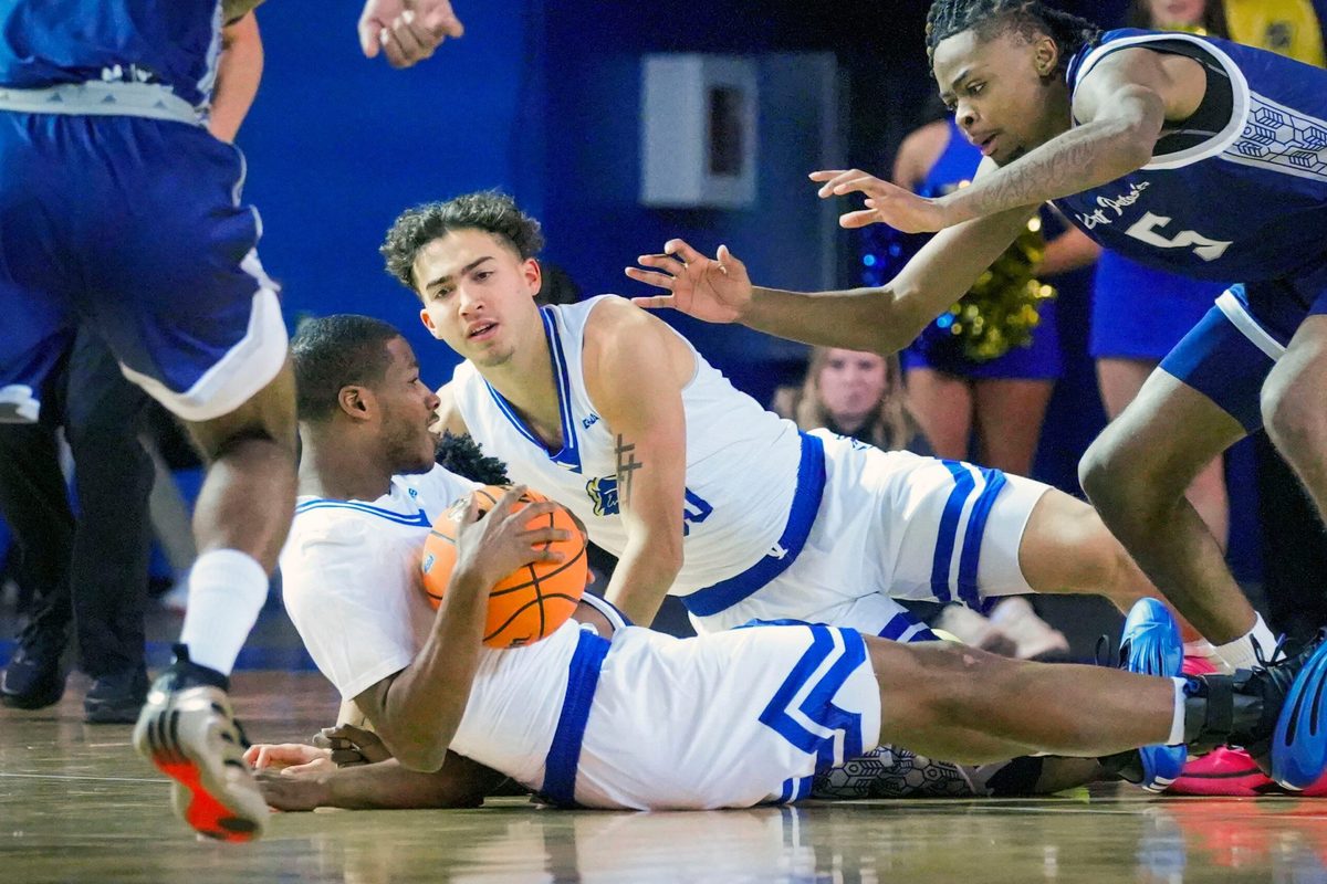 Delaware’s Jameel Brown (bottom) and Christian Bliss move for a loose ball ahead of Saint Peter’s Jahki Gupton in the first half of the Blue Hens’ 81-70 win at the Bob Carpenter Center, Nov. 18, 2025.