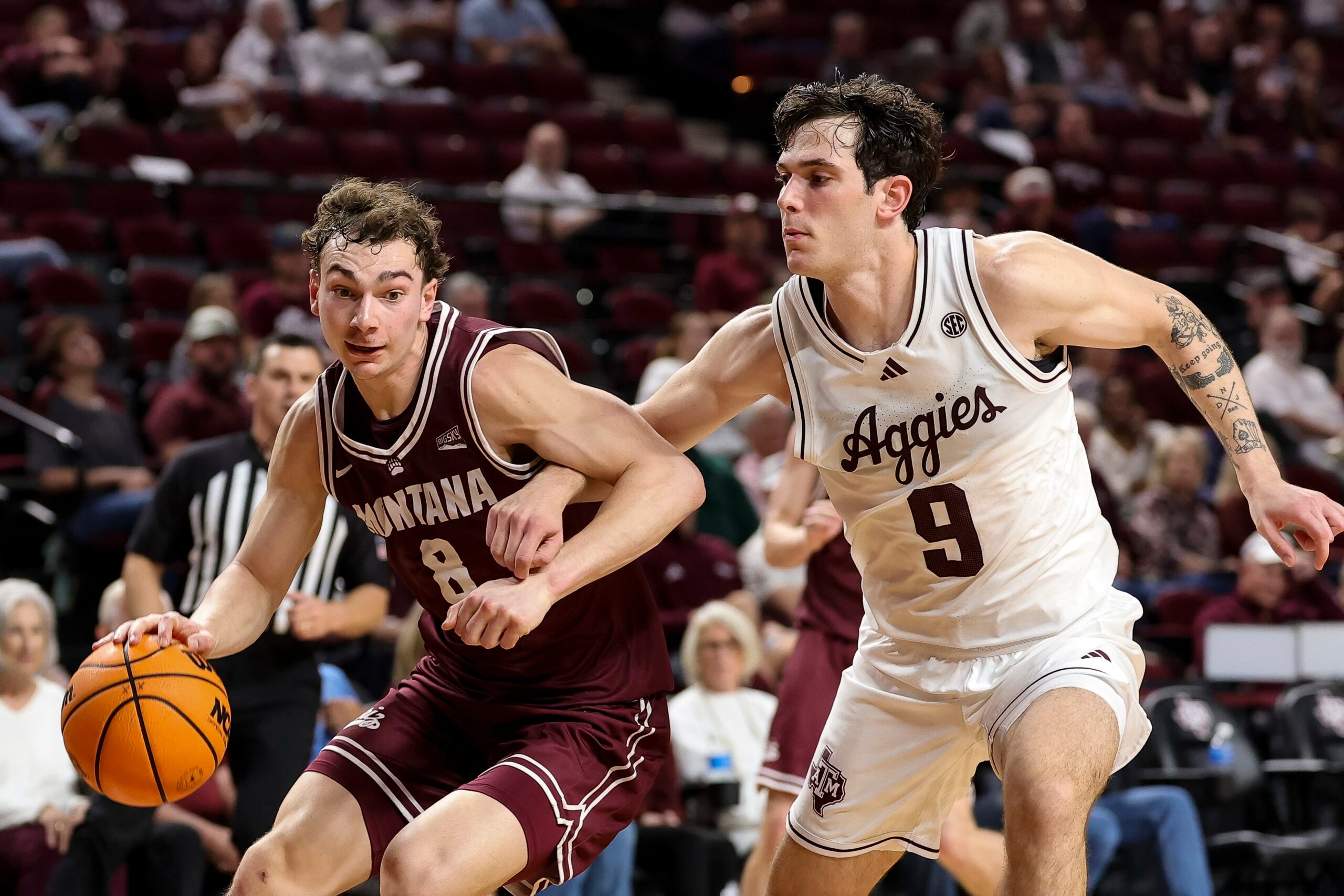 Nov 18, 2025; College Station, Texas, USA; Montana Grizzlies guard Tyler Isaak (8) drives as Texas A&M Aggies guard Ruben Dominguez (9) defends during the second half at Reed Arena. Mandatory Credit: Maria Lysaker-Imagn Images