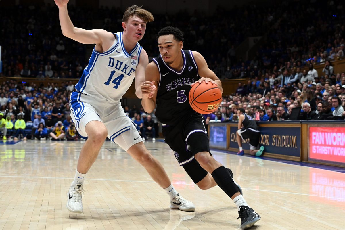 Nov 21, 2025; Durham, North Carolina, USA;Niagara Purple Eagles guard Justin Page (5) drives to the basket as Duke Blue Devils forward Nikolas Khamenia (14) defends during the first half at Cameron Indoor Stadium. Mandatory Credit: Rob Kinnan-Imagn Images