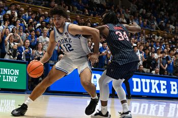 Nov 23, 2025; Durham, North Carolina, USA; Duke Blue Devils forward Cameron Boozer (12) drives to the basket as Howard Bison guard Bryce Harris (34) defends during the second half at Cameron Indoor Stadium. Mandatory Credit: Rob Kinnan-Imagn Images