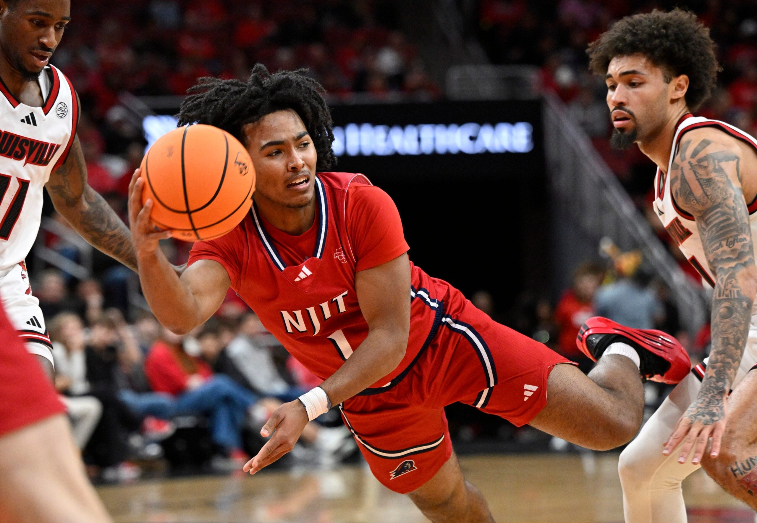 Nov 26, 2025; Louisville, Kentucky, USA;  NJIT Highlanders guard David Bolden (1) tries to pass against Louisville Cardinals guard J'Vonne Hadley (1) during the first half at KFC Yum! Center. Mandatory Credit: Jamie Rhodes-Imagn Images