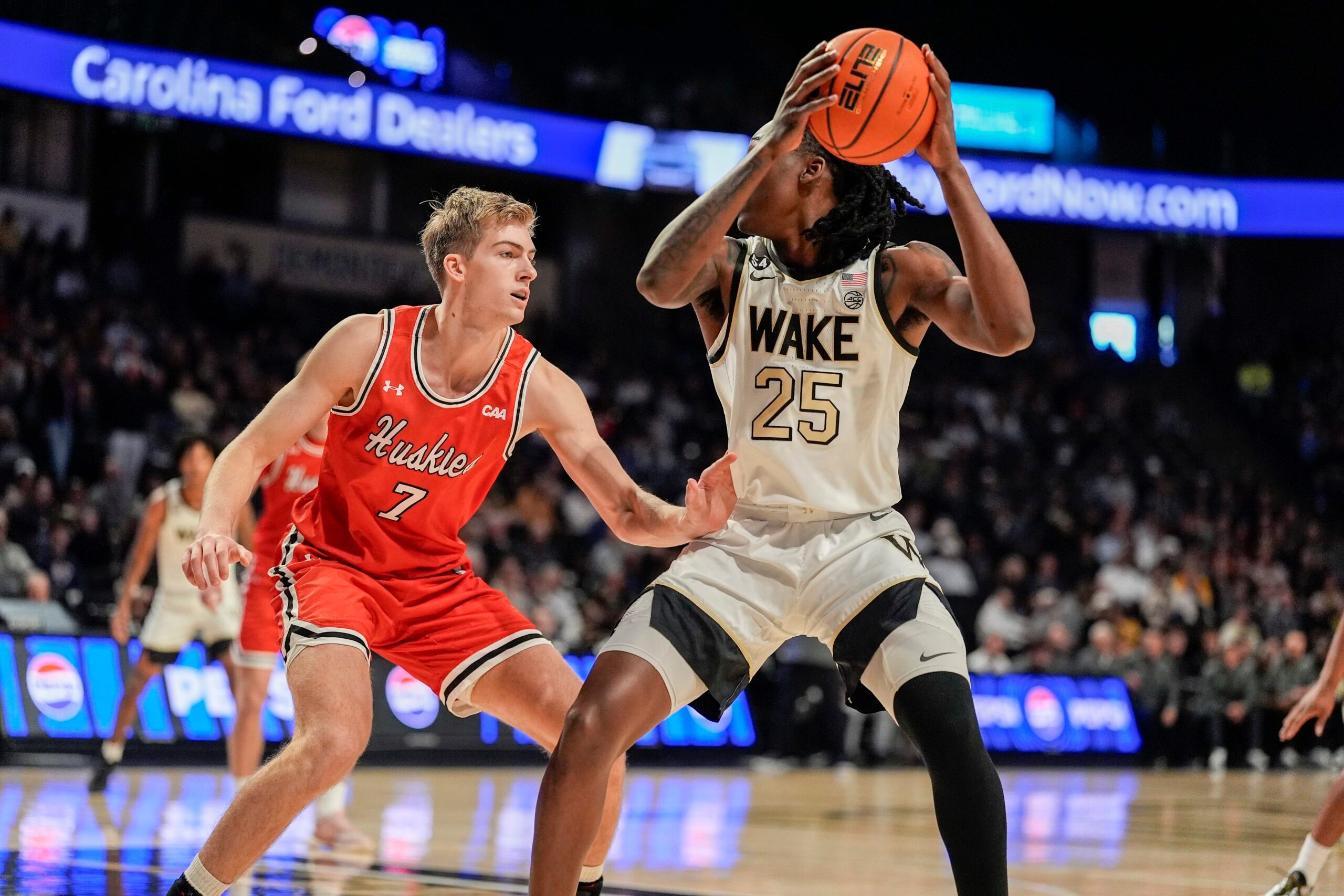 Nov 28, 2025; Winston-Salem, North Carolina, USA;  Wake Forest Demon Deacons forward Tre'Von Spillers (25) handles the ball against Northeastern Huskies forward Youri Fritz (7) during the first half at Lawrence Joel Veterans Memorial Coliseum. Mandatory Credit: Jim Dedmon-Imagn Images