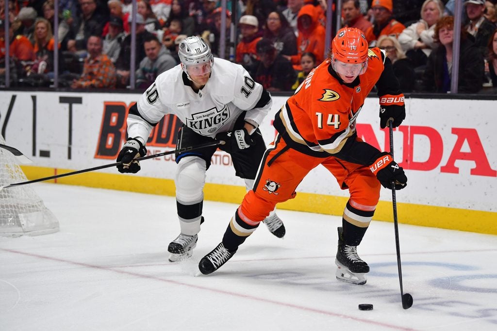 Nov 28, 2025; Anaheim, California, USA; Anaheim Ducks defenseman Drew Helleson (14) moves the puck ahead of Los Angeles Kings right wing Corey Perry (10) during the third period at Honda Center. Mandatory Credit: Gary A. Vasquez-Imagn Images