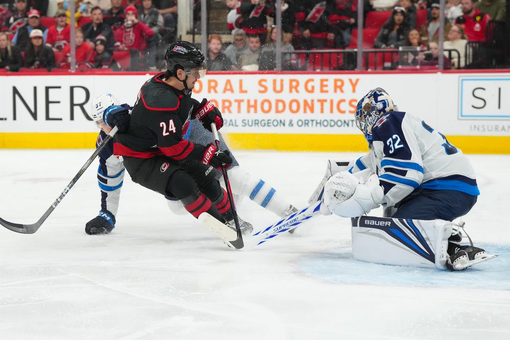Nov 28, 2025; Raleigh, North Carolina, USA; Carolina Hurricanes center Seth Jarvis (24) is stopped on his scoring attempt by Winnipeg Jets goaltender Thomas Milic (32) during the third period at Lenovo Center. Mandatory Credit: James Guillory-Imagn Images