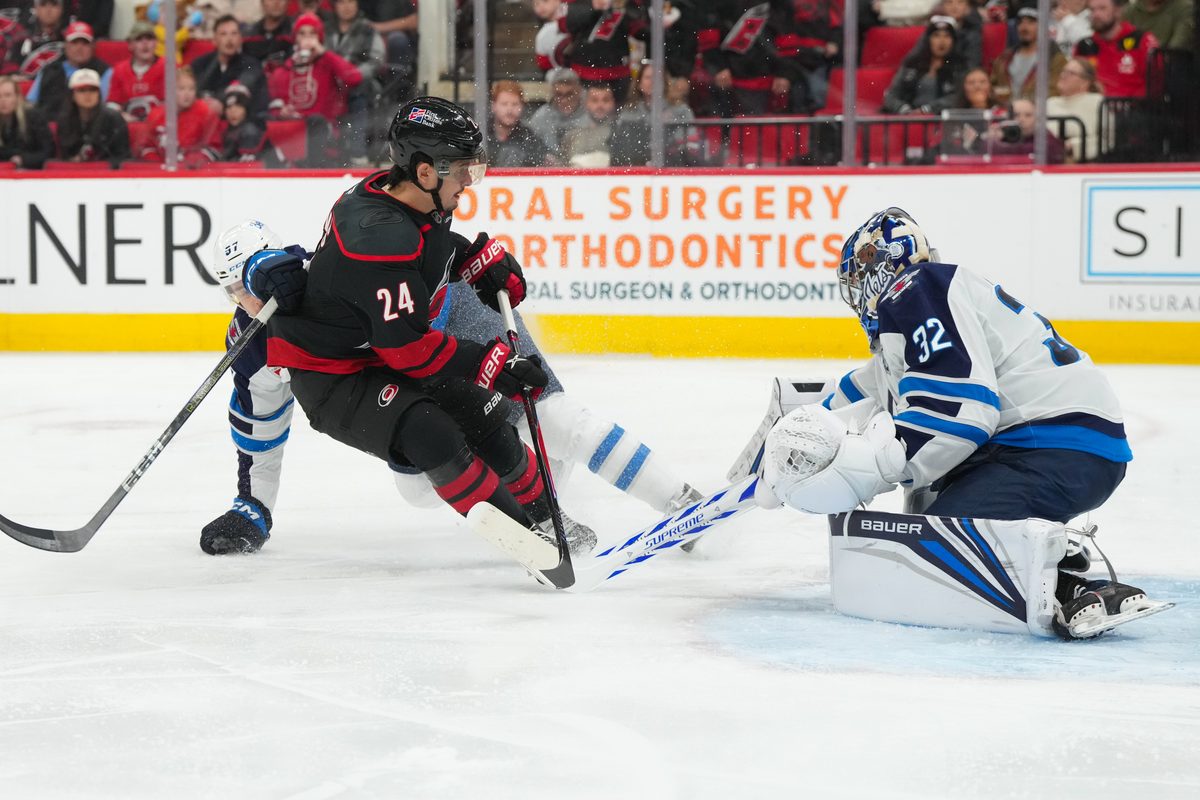 Nov 28, 2025; Raleigh, North Carolina, USA; Carolina Hurricanes center Seth Jarvis (24) is stopped on his scoring attempt by Winnipeg Jets goaltender Thomas Milic (32) during the third period at Lenovo Center. Mandatory Credit: James Guillory-Imagn Images