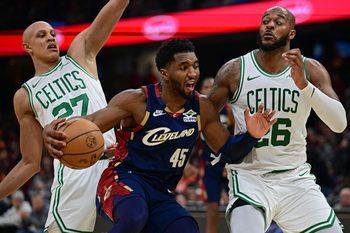 Nov 30, 2025; Cleveland, Ohio, USA; Cleveland Cavaliers guard Donovan Mitchell (45) drives on Boston Celtics forward Xavier Tillman (26) and guard Jordan Walsh (27) during the second half at Rocket Arena. Mandatory Credit: David Dermer-Imagn Images