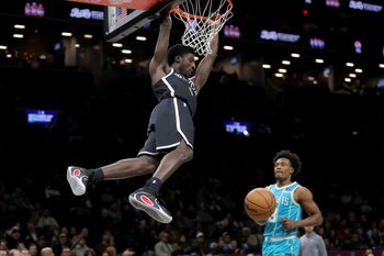 Dec 1, 2025; Brooklyn, New York, USA; Brooklyn Nets guard Drake Powell (4) hangs on the rim after a dunk against Charlotte Hornets guard Collin Sexton (8) during the third quarter at Barclays Center. Mandatory Credit: Brad Penner-Imagn Images