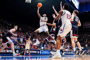 Dec 2, 2025; Lawrence, Kansas, USA; Kansas Jayhawks guard Melvin Council Jr. (14) shoots as UConn Huskies guard Braylon Mullins (24) looks on during the second half of the game at Allen Fieldhouse. Mandatory Credit: Denny Medley-Imagn Images