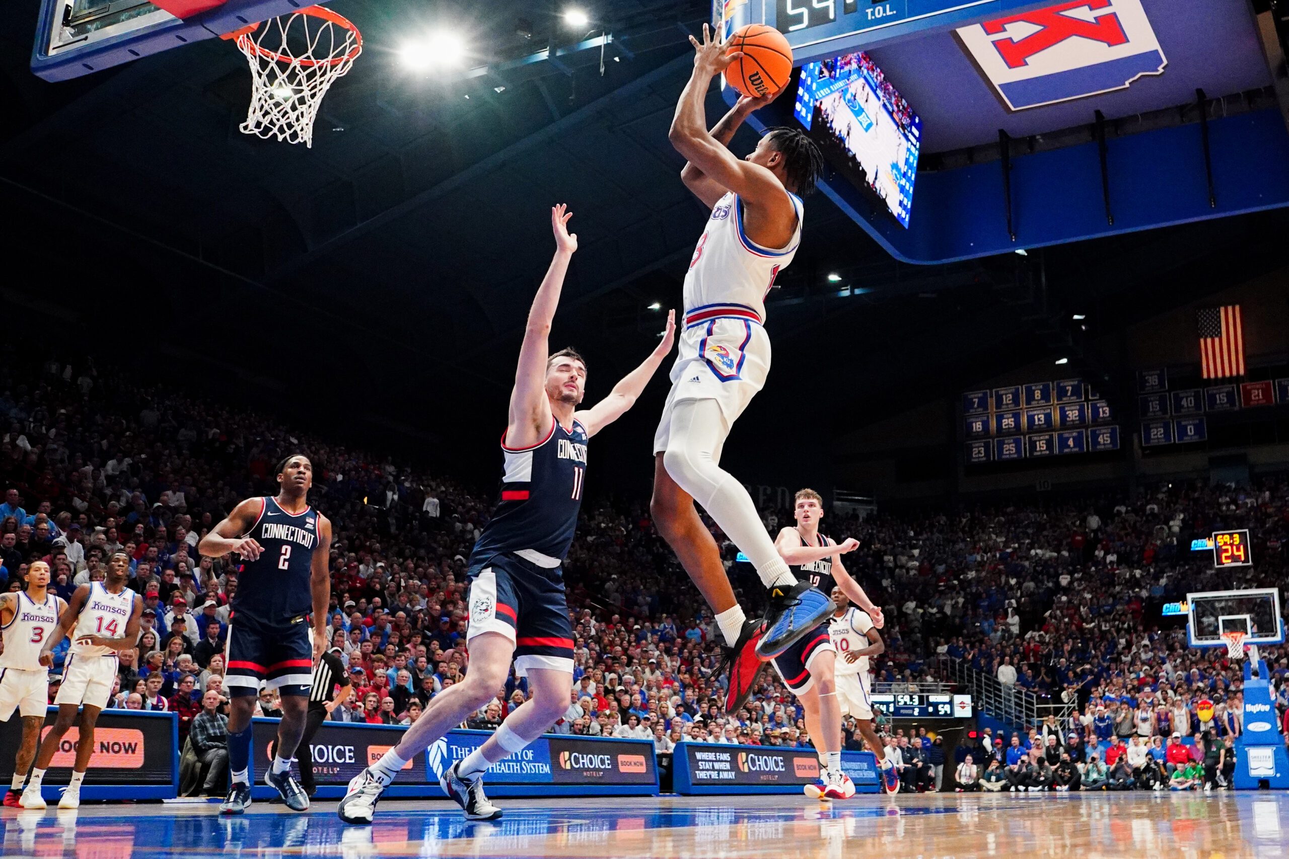 Dec 2, 2025; Lawrence, Kansas, USA; Kansas Jayhawks guard Elmarko Jackson (13) shoots as UConn Huskies forward Alex Karaban (11) defends during the second half of the game at Allen Fieldhouse. Mandatory Credit: Denny Medley-Imagn Images