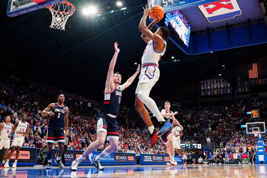 Dec 2, 2025; Lawrence, Kansas, USA; Kansas Jayhawks guard Elmarko Jackson (13) shoots as UConn Huskies forward Alex Karaban (11) defends during the second half of the game at Allen Fieldhouse. Mandatory Credit: Denny Medley-Imagn Images