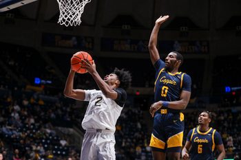 Dec 3, 2025; Morgantown, West Virginia, USA; West Virginia Mountaineers guard Amir Jenkins (2) shoots in the lane while defended by Coppin State Eagles guard Baasil Saunders (0) during the second half at Hope Coliseum. Mandatory Credit: Ben Queen-Imagn Images