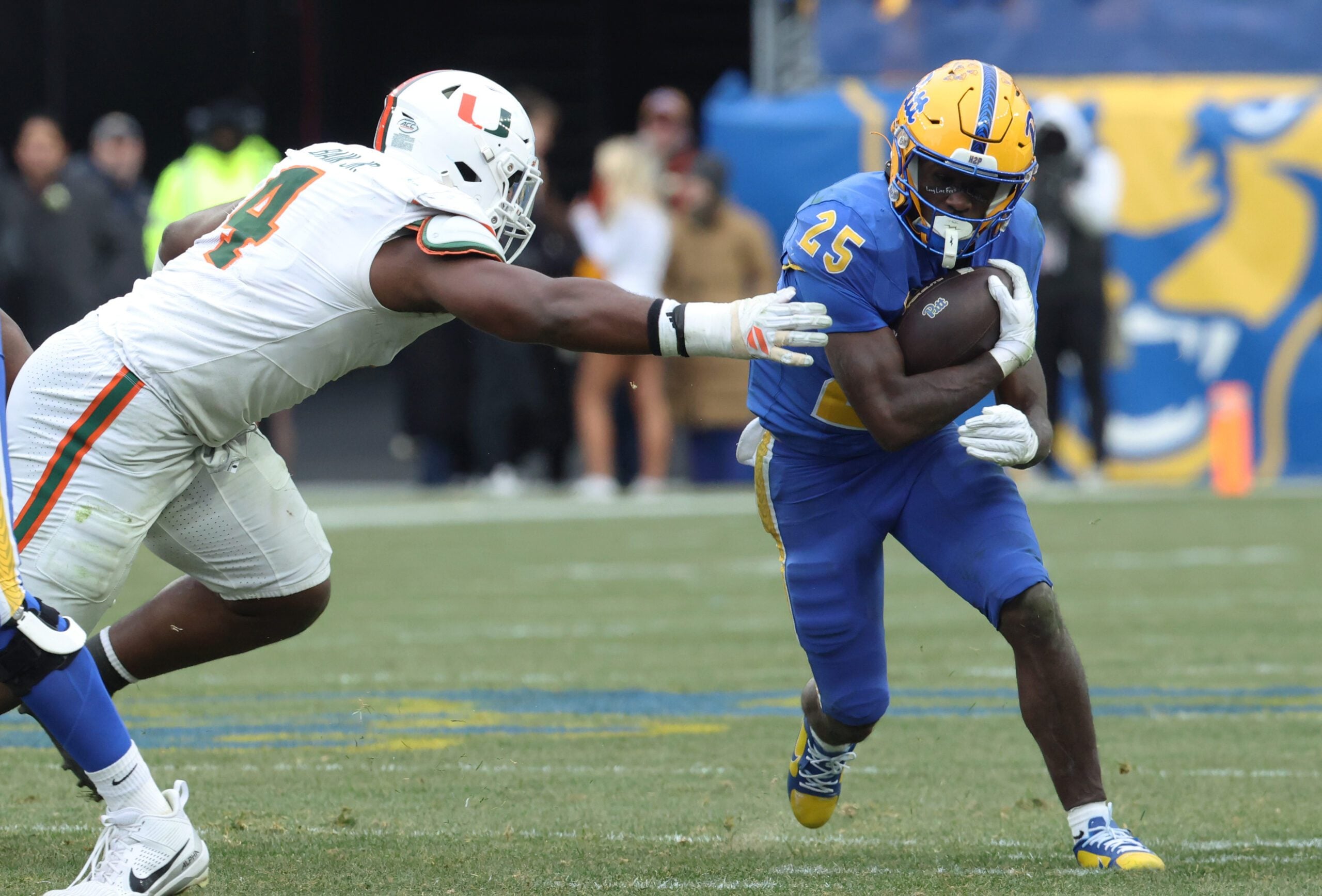 Nov 29, 2025; Pittsburgh, Pennsylvania, USA;  Pittsburgh Panthers running back Ja'Kyrian Turner (25) runs the ball against Miami Hurricanes defensive lineman Rueben Bain Jr. (4) during the third quarter at Acrisure Stadium. Mandatory Credit: Charles LeClaire-Imagn Images