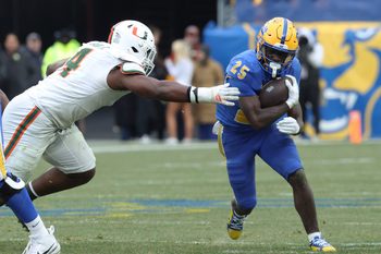 Nov 29, 2025; Pittsburgh, Pennsylvania, USA;  Pittsburgh Panthers running back Ja'Kyrian Turner (25) runs the ball against Miami Hurricanes defensive lineman Rueben Bain Jr. (4) during the third quarter at Acrisure Stadium. Mandatory Credit: Charles LeClaire-Imagn Images