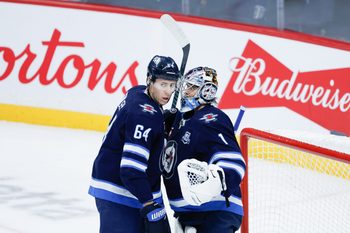 Dec 5, 2025; Winnipeg, Manitoba, CAN;  Winnipeg Jets goalie Eric Comrie (1) is congratulated by defenseman Logan Stanley (64) on his win against the Buffalo Sabres during the third period at Canada Life Centre. Mandatory Credit: Terrence Lee-Imagn Images