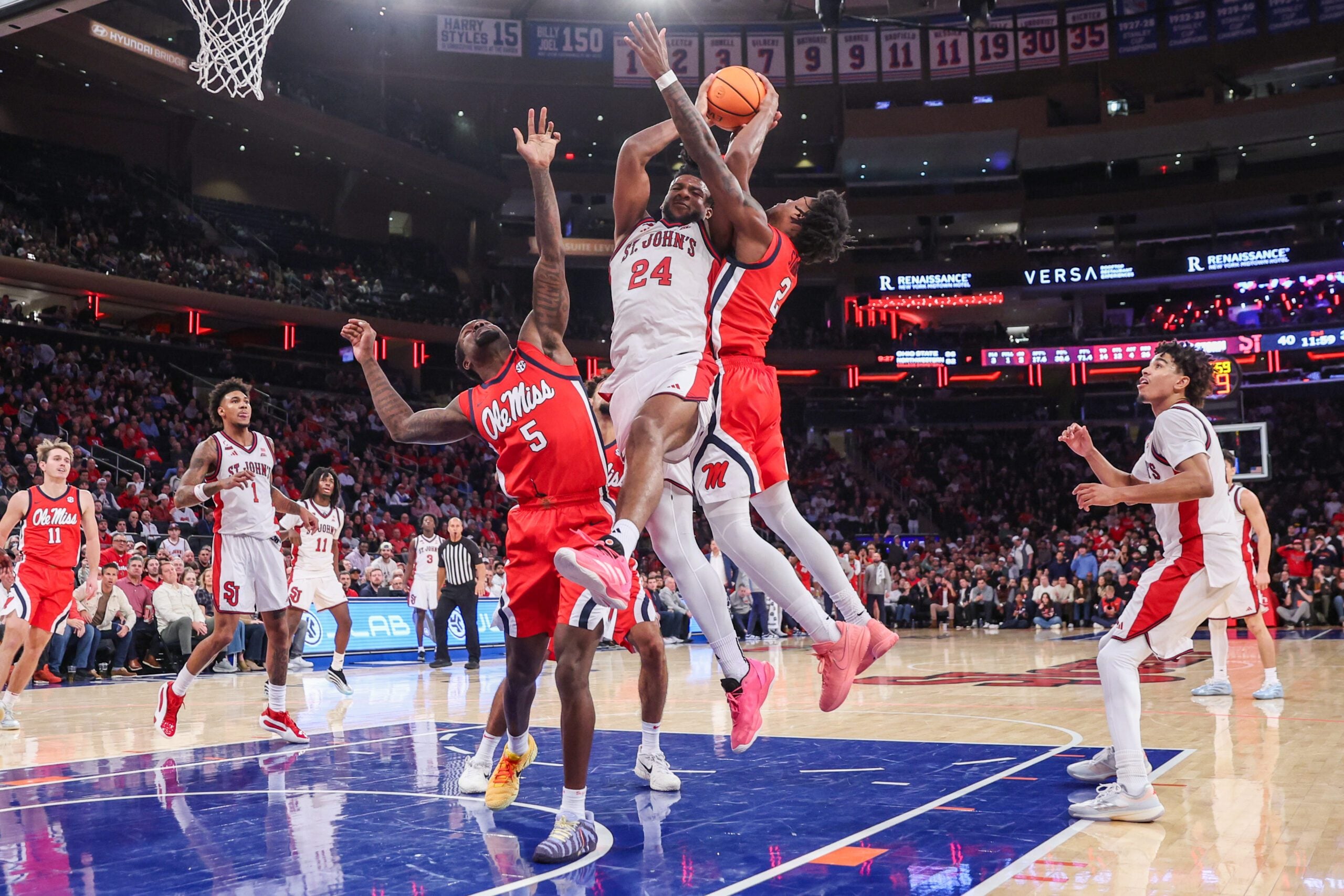 Dec 6, 2025; New York, New York, USA;  St. John's Red Storm forward Zuby Ejiofor (24) grabs a rebound from Mississippi Rebels guards Hobert Grayson IV (5) and AJ Storr (2) in the second half at Madison Square Garden. Mandatory Credit: Wendell Cruz-Imagn Images