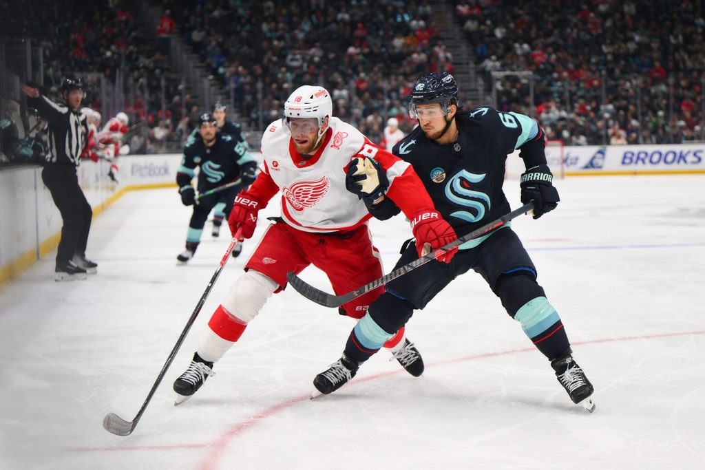 Dec 6, 2025; Seattle, Washington, USA; Detroit Red Wings center Andrew Copp (18) and Seattle Kraken defenseman Brandon Montour (62) chases the loose puck during the third period at Climate Pledge Arena. Mandatory Credit: Steven Bisig-Imagn Images