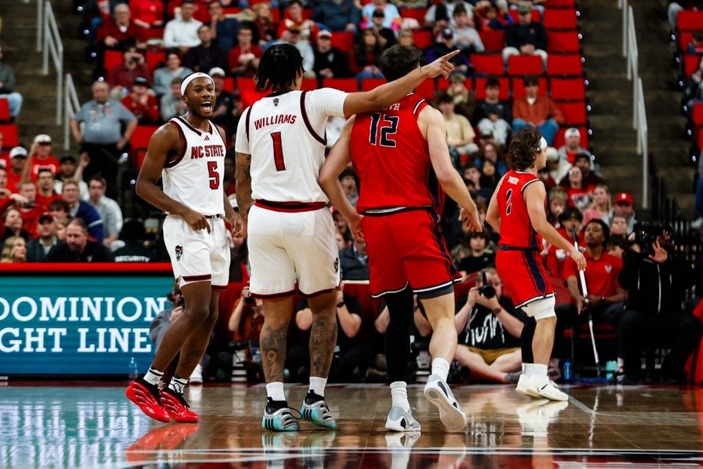 Dec 6, 2025; Raleigh, North Carolina, USA; NC State Wolfpack forward Darrion Williams (1) celebrates a three point shot over Liberty Flames forward Josh Smith (12) during the second half of the game at Lenovo Center. Mandatory Credit: Jaylynn Nash-Imagn Images