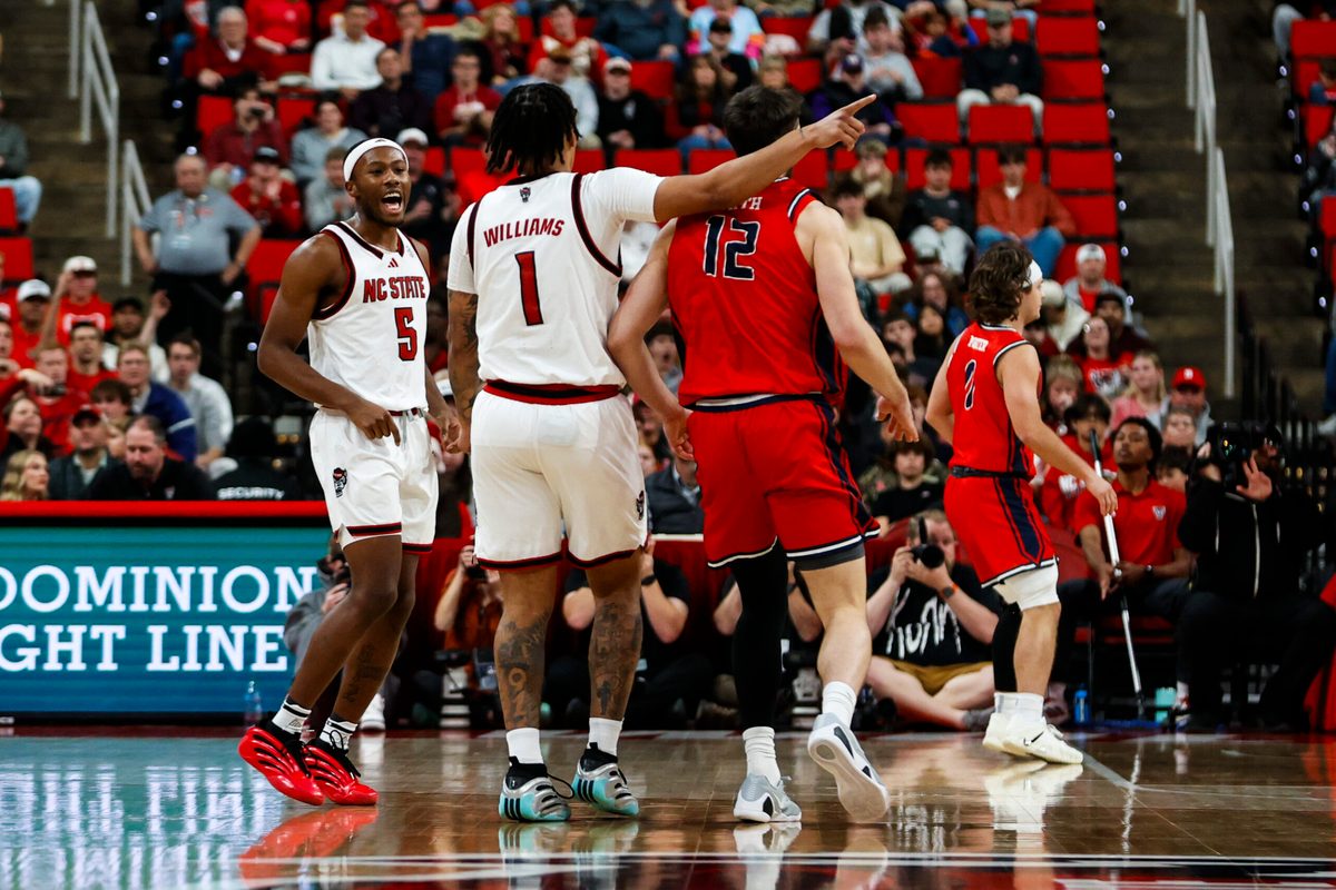 Dec 6, 2025; Raleigh, North Carolina, USA; NC State Wolfpack forward Darrion Williams (1) celebrates a three point shot over Liberty Flames forward Josh Smith (12) during the second half of the game at Lenovo Center. Mandatory Credit: Jaylynn Nash-Imagn Images