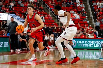 Dec 6, 2025; Raleigh, North Carolina, USA; Liberty Flames forward Zach Cleveland (25) dribbles the ball guarded by NC State Wolfpack guard Quadir Copeland (11) during the second half of the game at Lenovo Center. Mandatory Credit: Jaylynn Nash-Imagn Images