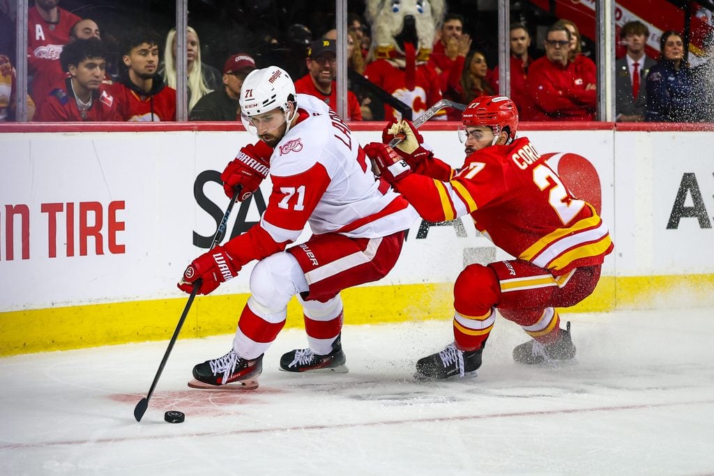 Dec 10, 2025; Calgary, Alberta, CAN; Detroit Red Wings center Dylan Larkin (71) and Calgary Flames right wing Matt Coronato (27) battle for the puck during the third period at Scotiabank Saddledome. Mandatory Credit: Sergei Belski-Imagn Images