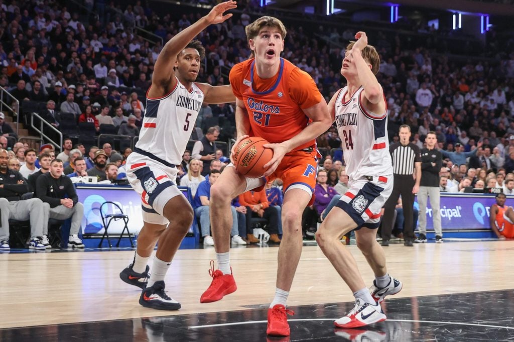 Dec 9, 2025; New York, New York, USA; Florida Gators forward Alex Condon (21) and UConn Huskies forward Tarris Reed Jr. (5) and guard Braylon Mullins (24) at Madison Square Garden. Mandatory Credit: Wendell Cruz-Imagn Images