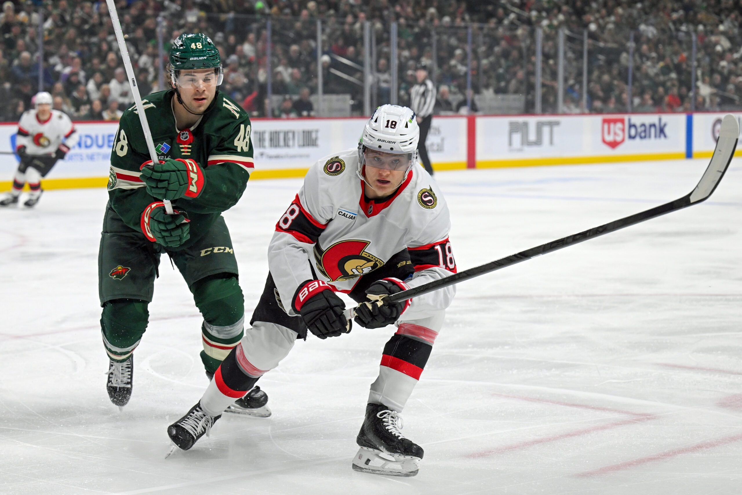 Dec 13, 2025; Saint Paul, Minnesota, USA;  .Minnesota Wild defensemen Daemon Hunt (48) and Ottawa Senators forward Tim Stutzle (18) chase after a loose puck during the first period at Grand Casino Arena. Mandatory Credit: Nick Wosika-Imagn Images