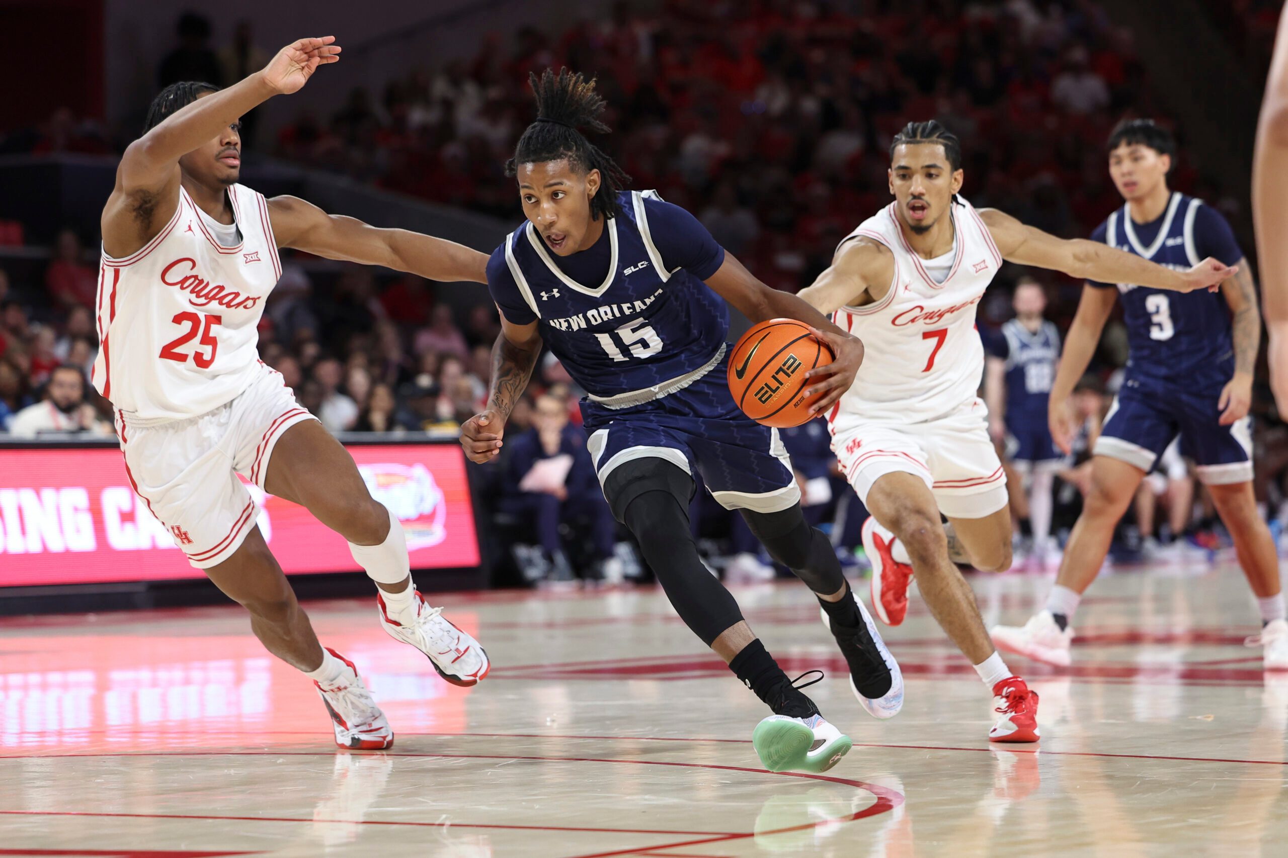 Dec 13, 2025; Houston, Texas, USA; New Orleans Privateers guard Jamal Chretien II (15) drives with the ball as Houston Cougars guard Milos Uzan (7) defends during the first half at Fertitta Center. Mandatory Credit: Troy Taormina-Imagn Images