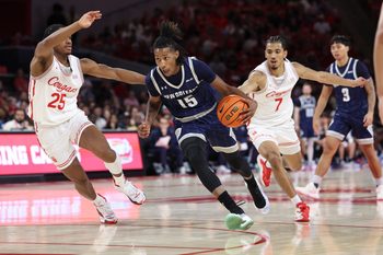 Dec 13, 2025; Houston, Texas, USA; New Orleans Privateers guard Jamal Chretien II (15) drives with the ball as Houston Cougars guard Milos Uzan (7) defends during the first half at Fertitta Center. Mandatory Credit: Troy Taormina-Imagn Images
