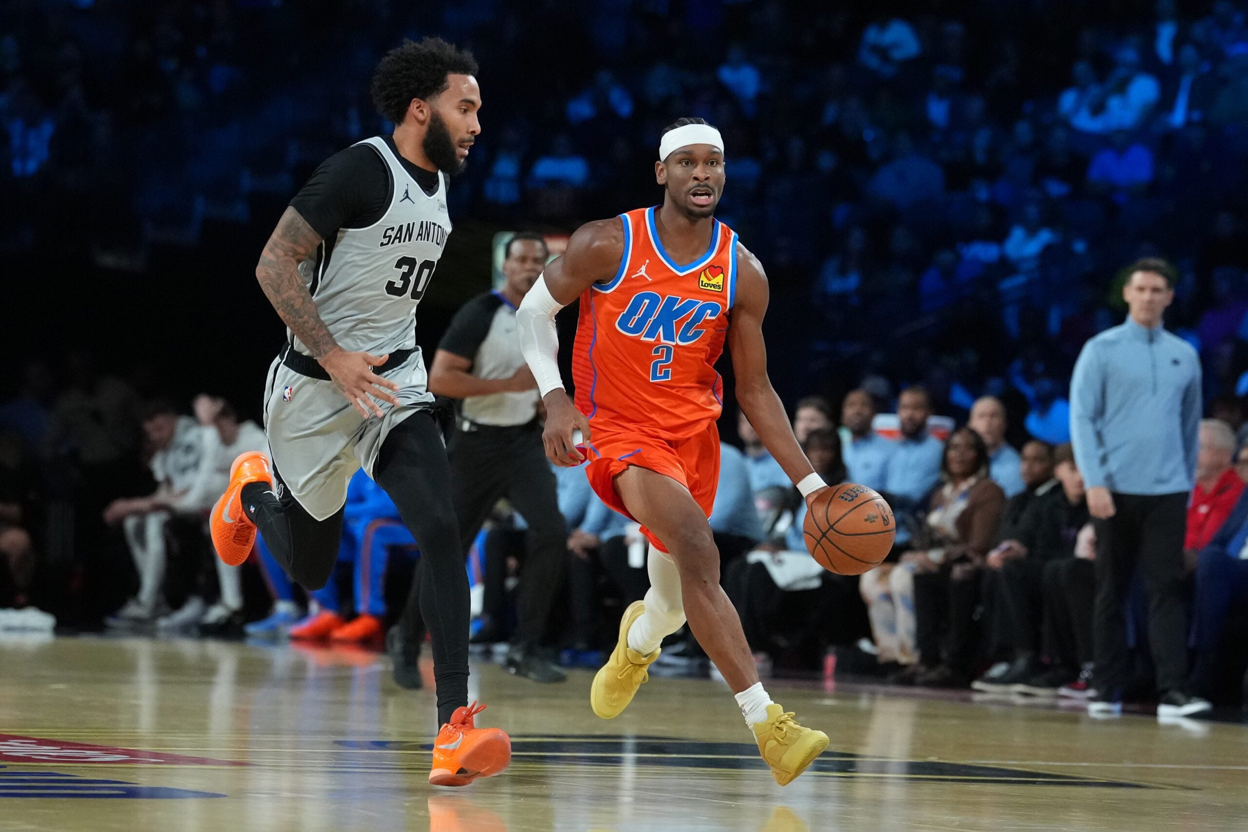 Dec 13, 2025; Las Vegas, Nevada, USA; Oklahoma City Thunder guard Shai Gilgeous-Alexander (2) brings the ball up court as San Antonio Spurs forward Julian Champagnie (30) defends during the first quarter at T-Mobile Arena. Mandatory Credit: Kirby Lee-Imagn Images