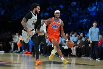 Dec 13, 2025; Las Vegas, Nevada, USA; Oklahoma City Thunder guard Shai Gilgeous-Alexander (2) brings the ball up court as San Antonio Spurs forward Julian Champagnie (30) defends during the first quarter at T-Mobile Arena. Mandatory Credit: Kirby Lee-Imagn Images