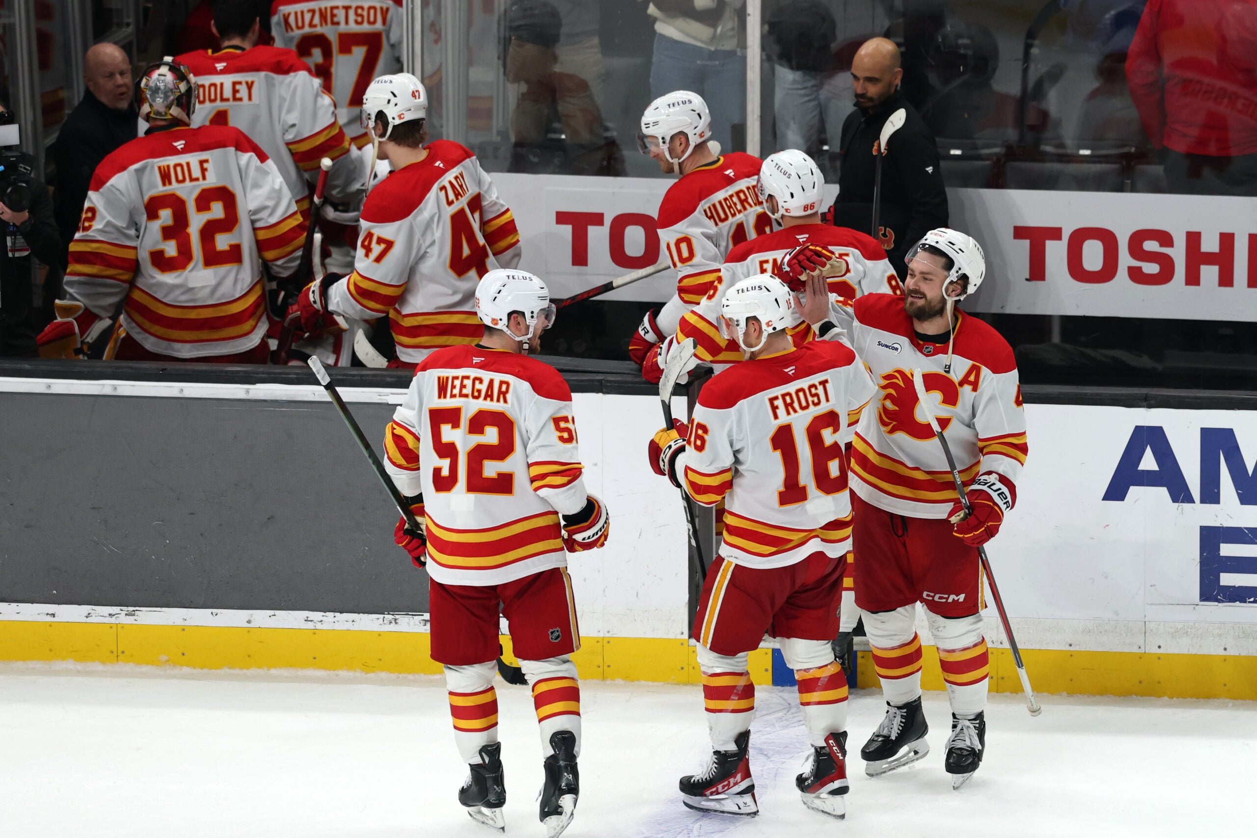 Dec 13, 2025; Los Angeles, California, USA;  Calgary Flames center Morgan Frost (16) celebrates with defenseman Mackenzie Weegar (52) and defenseman Rasmus Andersson (right) after defeating the Los Angeles Kings in overtime at Crypto.com Arena. Mandatory Credit: Kiyoshi Mio-Imagn Images