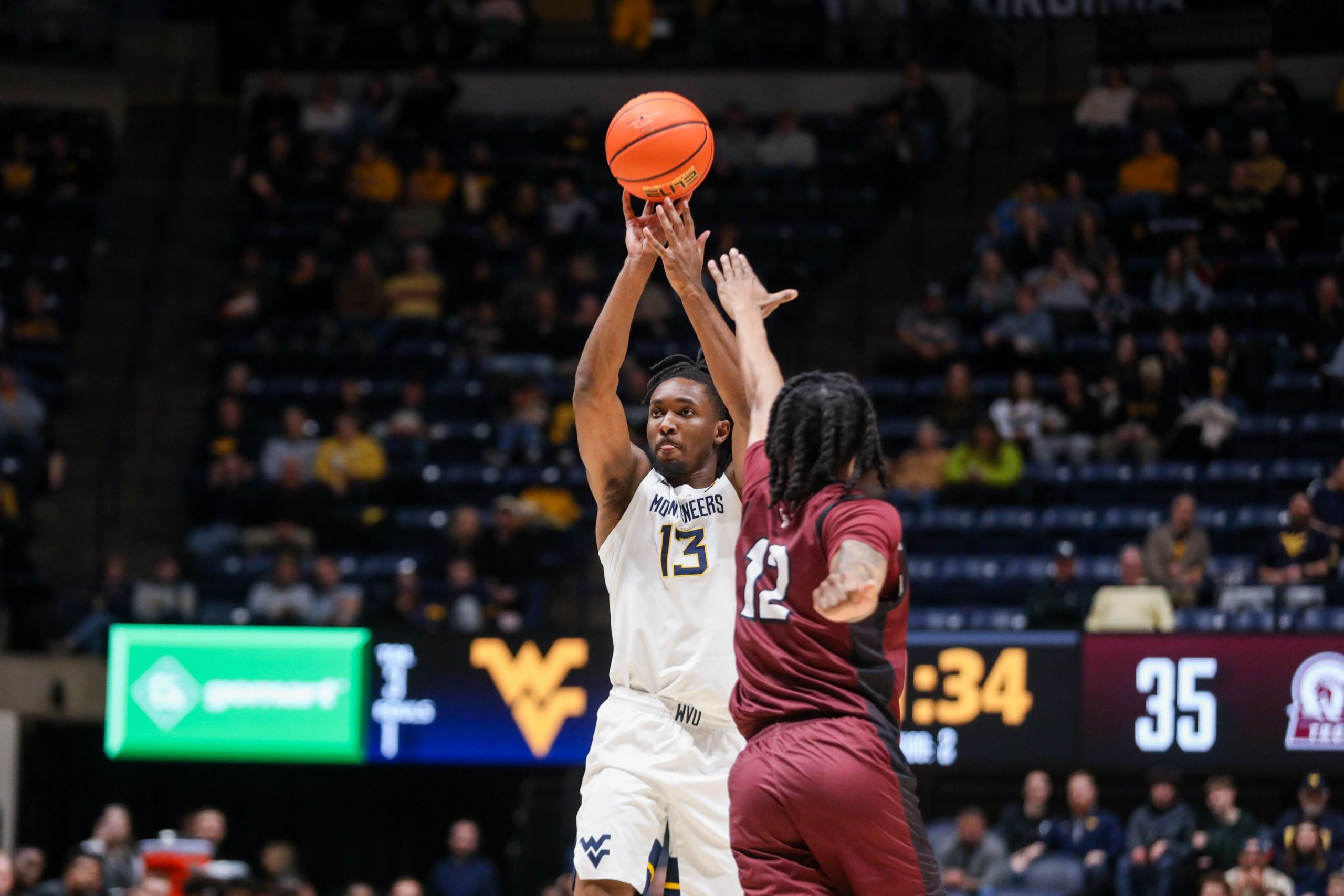 Dec 9, 2025; Morgantown, West Virginia, USA; West Virginia Mountaineers guard Chance Moore (13) shoots over Little Rock Trojans guard Tracy Steele Jr. (12) during the second half at Hope Coliseum. Mandatory Credit: Ben Queen-Imagn Images