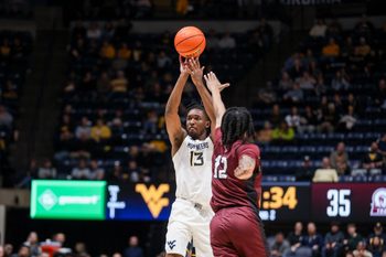 Dec 9, 2025; Morgantown, West Virginia, USA; West Virginia Mountaineers guard Chance Moore (13) shoots over Little Rock Trojans guard Tracy Steele Jr. (12) during the second half at Hope Coliseum. Mandatory Credit: Ben Queen-Imagn Images