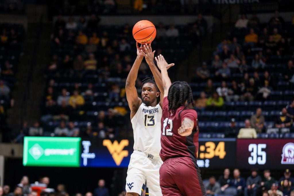 Dec 9, 2025; Morgantown, West Virginia, USA; West Virginia Mountaineers guard Chance Moore (13) shoots over Little Rock Trojans guard Tracy Steele Jr. (12) during the second half at Hope Coliseum. Mandatory Credit: Ben Queen-Imagn Images