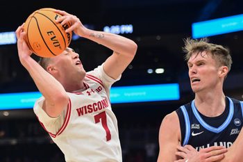Dec 19, 2025; Milwaukee, Wisconsin, USA; Wisconsin Badgers guard Andrew Rohde (7) grabs a rebound against Villanova Wildcats forward Duke Brennan (24) in the second half at the Fiserv Forum. Mandatory Credit: Benny Sieu-Imagn Images