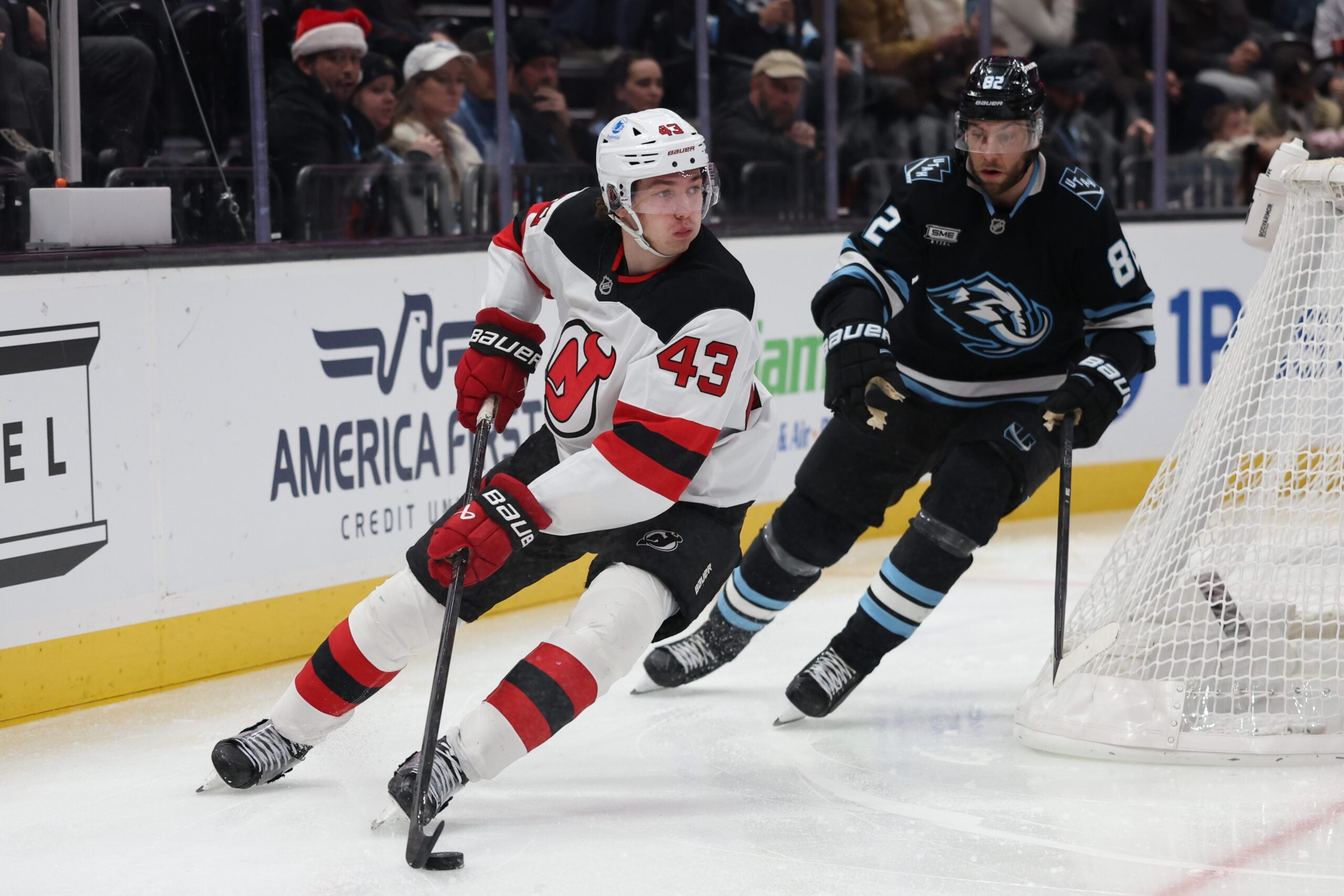 Dec 19, 2025; Salt Lake City, Utah, USA; New Jersey Devils defenseman Luke Hughes (43) plays the puck against Utah Mammoth center Kevin Stenlund (82) during the third period at Delta Center. Mandatory Credit: Rob Gray-Imagn Images