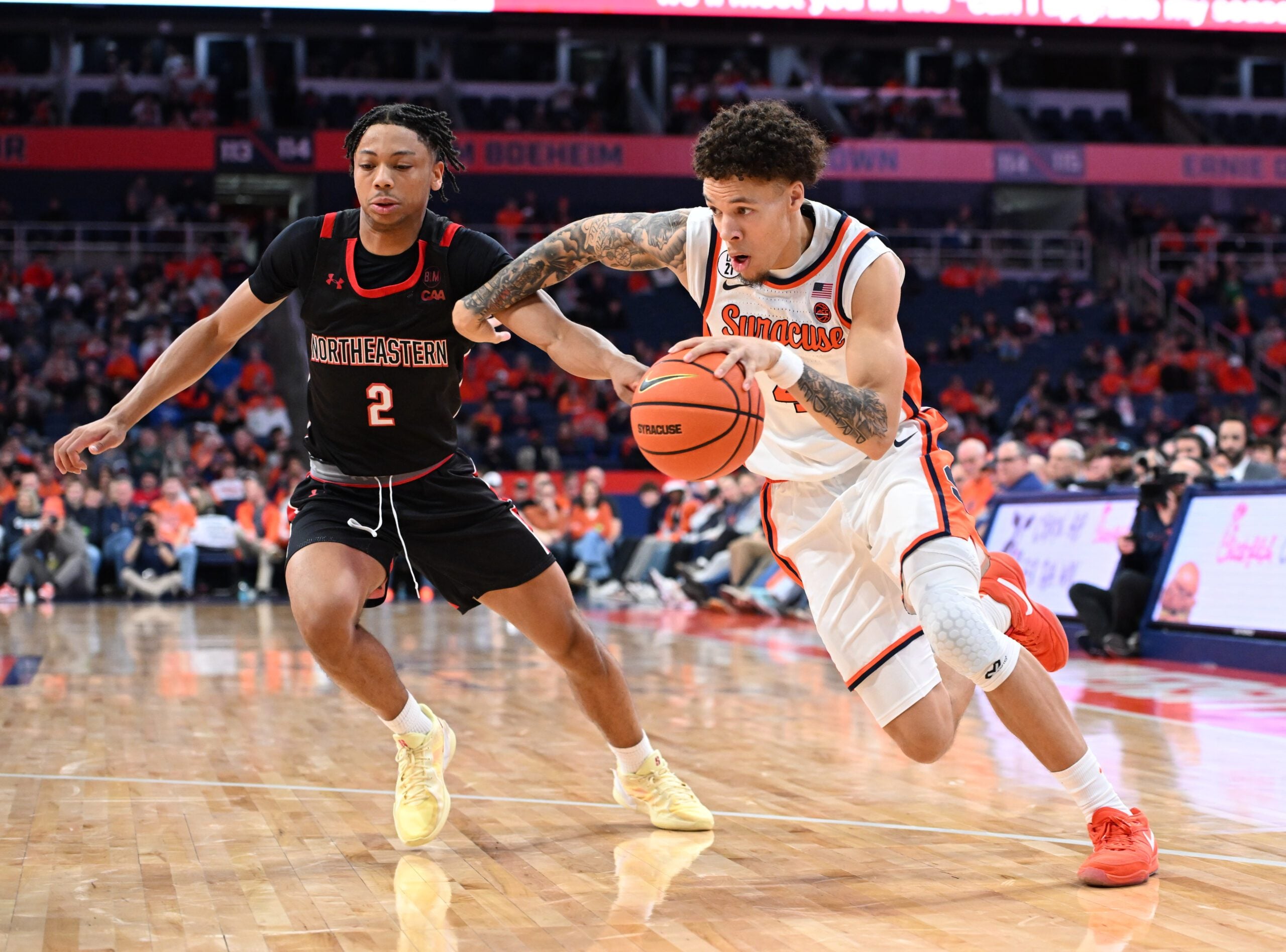 Dec 20, 2025; Syracuse, New York, USA; Syracuse Orange guard Nate Kingz (4) drives to the basket against Northeastern Huskies guard Ryan Williams (2) in the second half at the JMA Wireless Dome. Mandatory Credit: Mark Konezny-Imagn Images