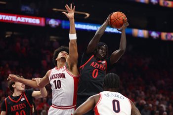 Dec 20, 2025; Phoenix, Arizona, USA; San Diego State Aztecs forward Magoon Gwath (0) grabs a rebound against Arizona Wildcats forward Koa Peat (10) during the Hall of Fame Series at Mortgage Matchup Center. Mandatory Credit: Mark J. Rebilas-Imagn Images