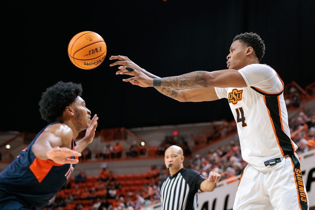 Dec 21, 2025; Stillwater, Oklahoma, USA; Oklahoma State Cowboys guard Christian Coleman (4) passes over Cal State Fullerton Titans guard Christian Williams (7) during the first half at Gallagher-Iba Arena. Mandatory Credit: William Purnell-Imagn Images