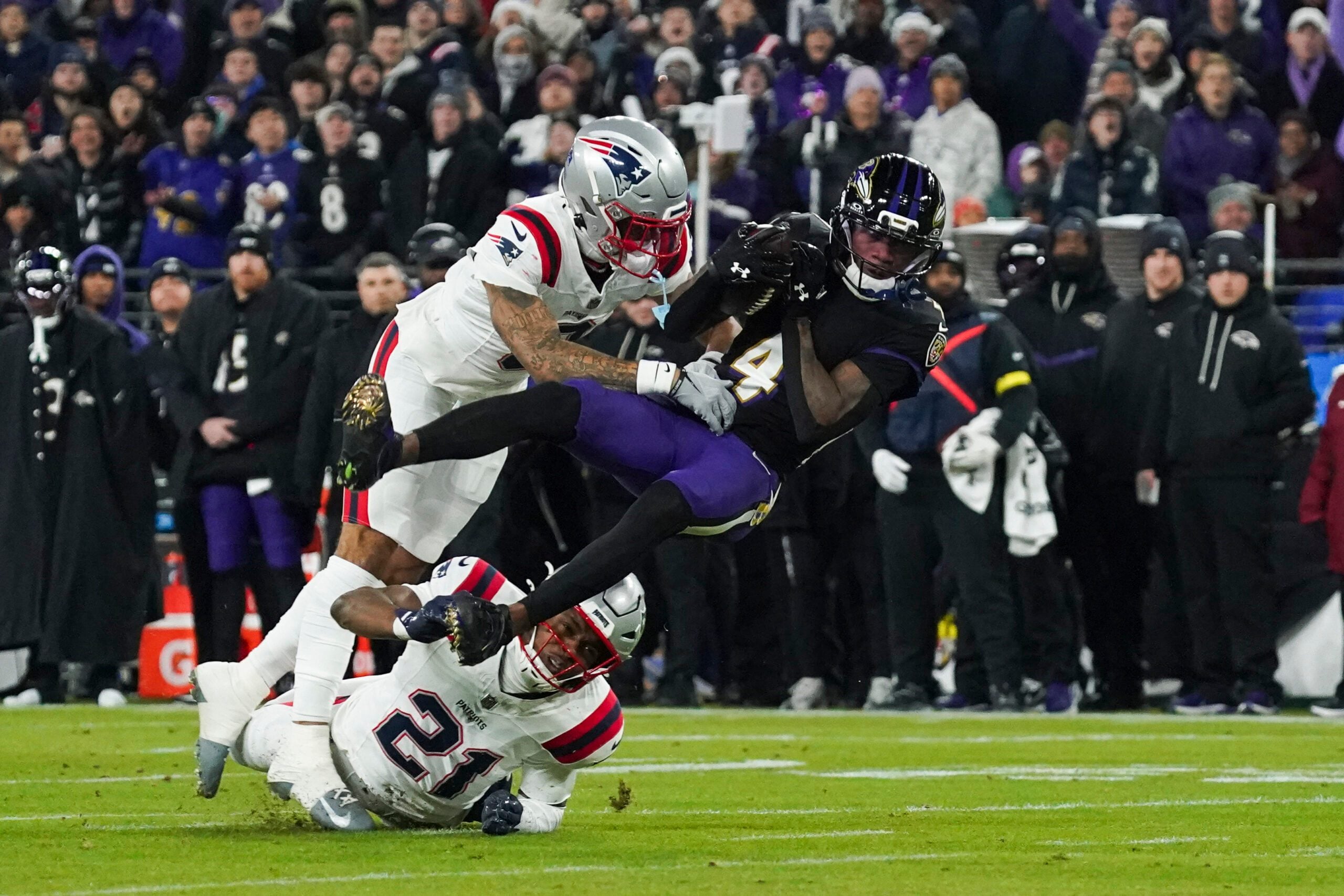Dec 21, 2025; Baltimore, Maryland, USA; Baltimore Ravens wide receiver Zay Flowers (4) is hit by New England Patriots cornerback Christian Gonzalez (0) during the first quarter of the game at M&T Bank Stadium. Mandatory Credit: James Lang-Imagn Images