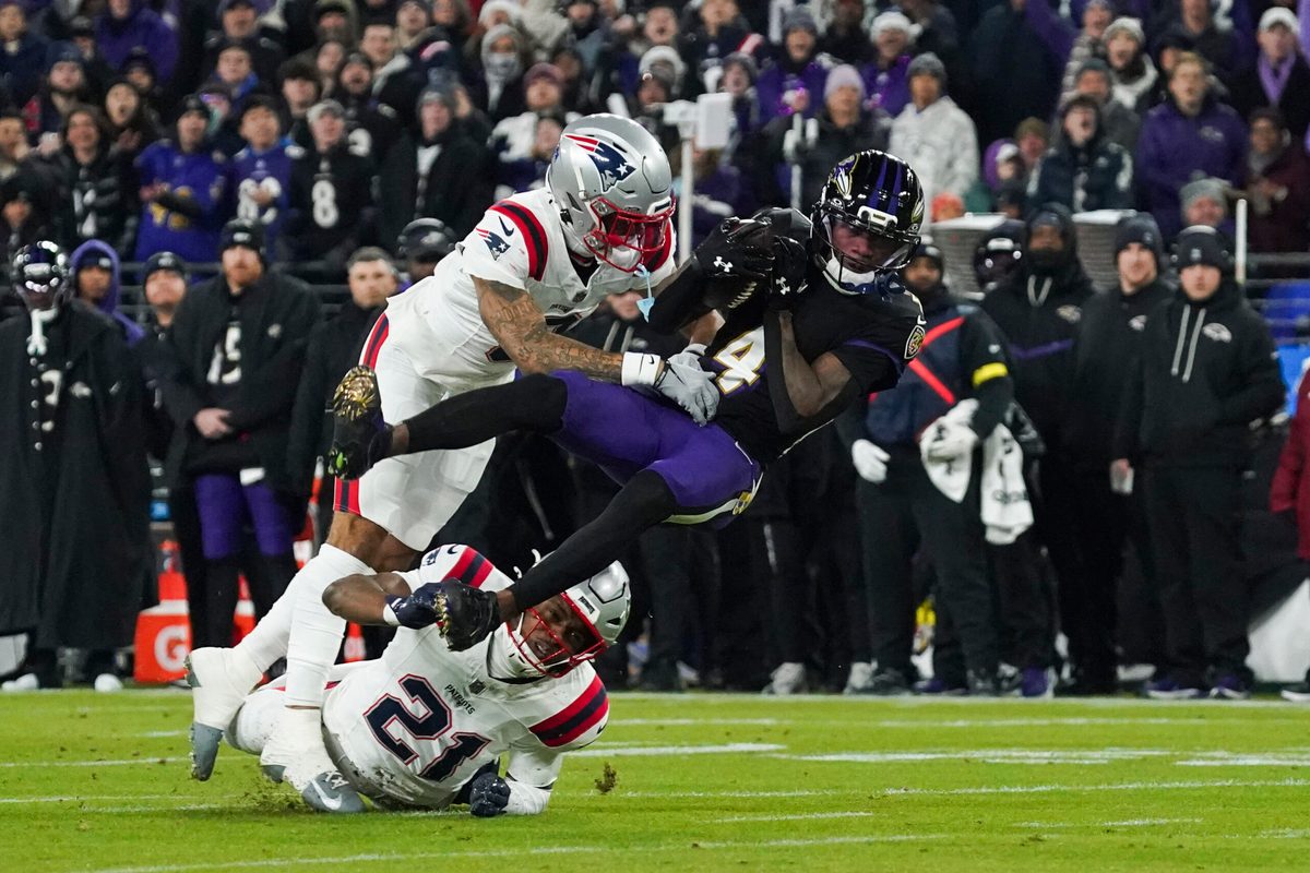 Dec 21, 2025; Baltimore, Maryland, USA;  Baltimore Ravens wide receiver Zay Flowers (4) is hit by New England Patriots cornerback Christian Gonzalez (0) during the first quarter of the game at M&T Bank Stadium. Mandatory Credit: James Lang-Imagn Images