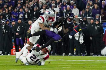 Dec 21, 2025; Baltimore, Maryland, USA;  Baltimore Ravens wide receiver Zay Flowers (4) is hit by New England Patriots cornerback Christian Gonzalez (0) during the first quarter of the game at M&T Bank Stadium. Mandatory Credit: James Lang-Imagn Images