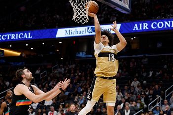 Dec 21, 2025; Washington, District of Columbia, USA; Washington Wizards forward Kyshawn George (18) shoots the ball as San Antonio Spurs center Luke Kornet (7) defends in the second half at Capital One Arena. Mandatory Credit: Geoff Burke-Imagn Images