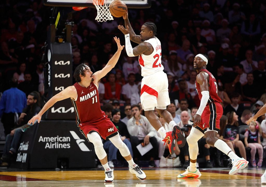 Dec 23, 2025; Miami, Florida, USA; Toronto Raptors guard Jamal Shead (23) passes between Miami Heat forward Jaime Jaquez Jr. (11) and center Bam Adebayo (13) during the second half at Kaseya Center. Mandatory Credit: Rhona Wise-Imagn Images