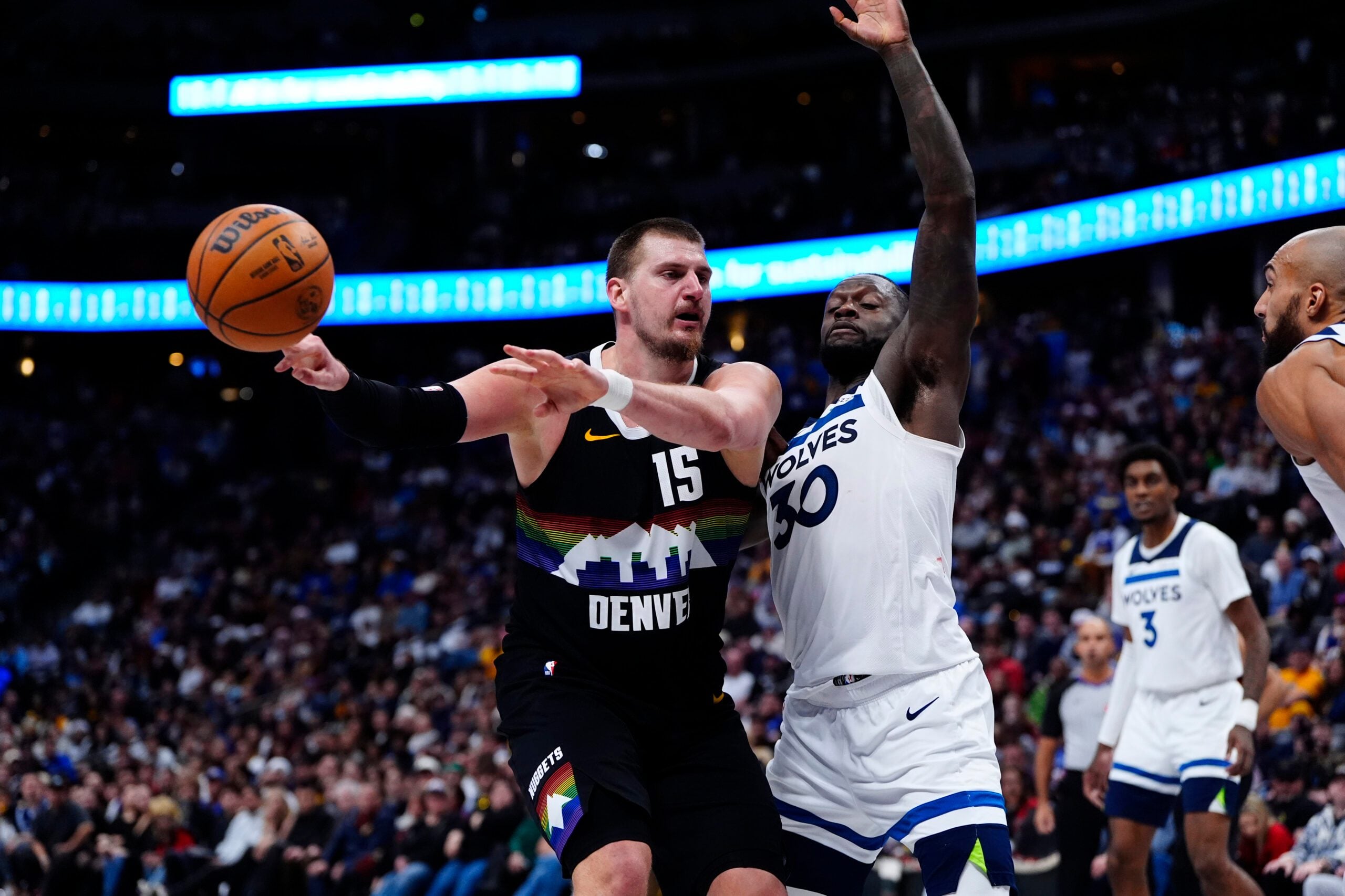 Dec 25, 2025; Denver, Colorado, USA; Denver Nuggets center Nikola Jokic (15) passes the ball away from Minnesota Timberwolves forward Julius Randle (30) in overtime at Ball Arena. Mandatory Credit: Ron Chenoy-Imagn Images