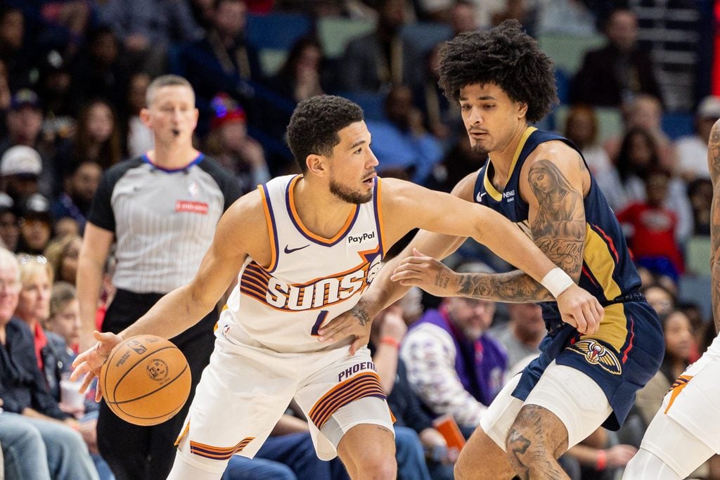 Dec 27, 2025; New Orleans, Louisiana, USA; Phoenix Suns guard Devin Booker (1) dribbles against New Orleans Pelicans guard/forward Micah Peavy (14) during the second half at Smoothie King Center. Mandatory Credit: Stephen Lew-Imagn Images