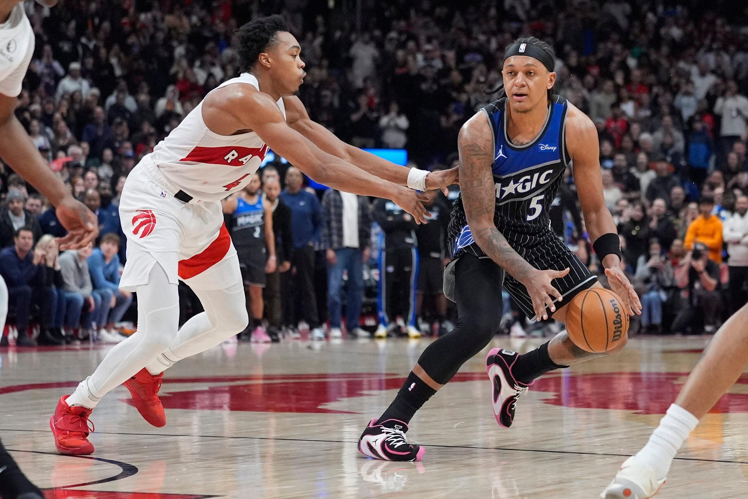 Dec 29, 2025; Toronto, Ontario, CAN; Orlando Magic forward Paolo Banchero (5) dribbles past Toronto Raptors guard Scottie Barnes (4) during the second half at Scotiabank Arena. Mandatory Credit: John E. Sokolowski-Imagn Images