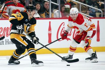Nov 30, 2024; Pittsburgh, Pennsylvania, USA;  Pittsburgh Penguins center Sidney Crosby (87) moves the puck against Calgary Flames center Yegor Sharangovich (17) during the third period at PPG Paints Arena. Mandatory Credit: Charles LeClaire-Imagn Images