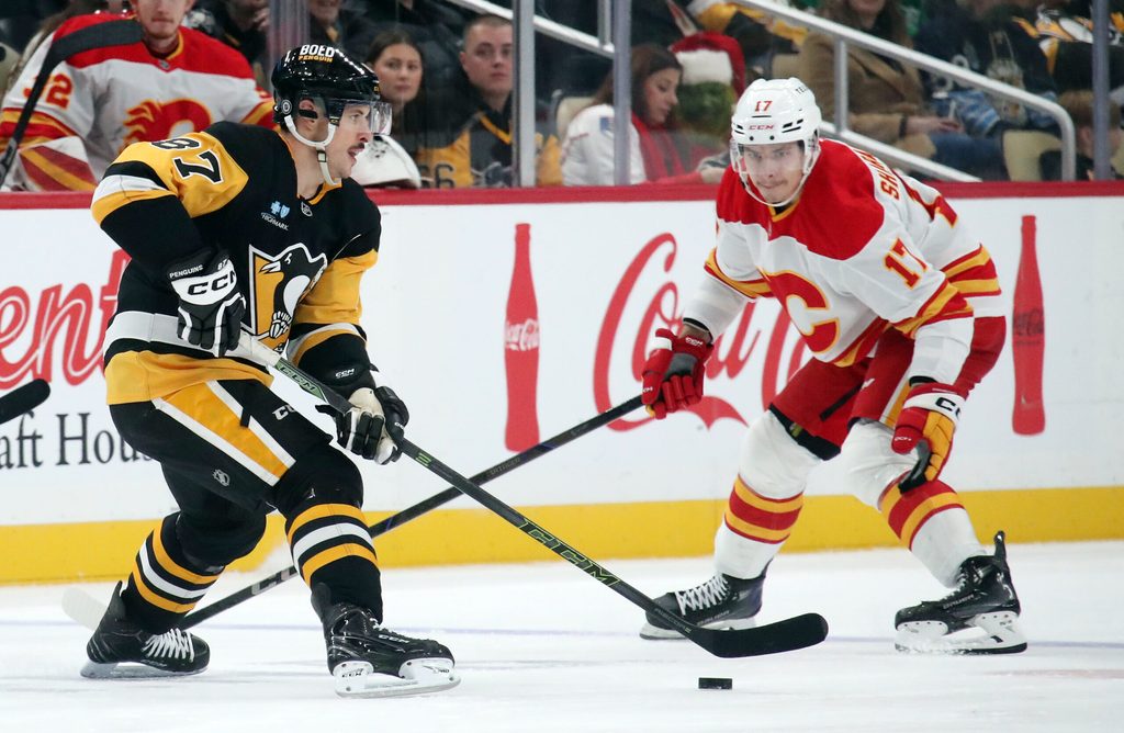 Nov 30, 2024; Pittsburgh, Pennsylvania, USA; Pittsburgh Penguins center Sidney Crosby (87) moves the puck against Calgary Flames center Yegor Sharangovich (17) during the third period at PPG Paints Arena. Mandatory Credit: Charles LeClaire-Imagn Images